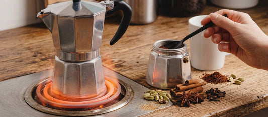 Cafetière italienne sur le feu à côté d'épices et de café moulu